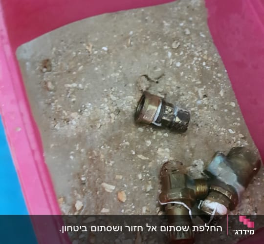 חלקי מתכת בתוך מיכל ורוד עם חול